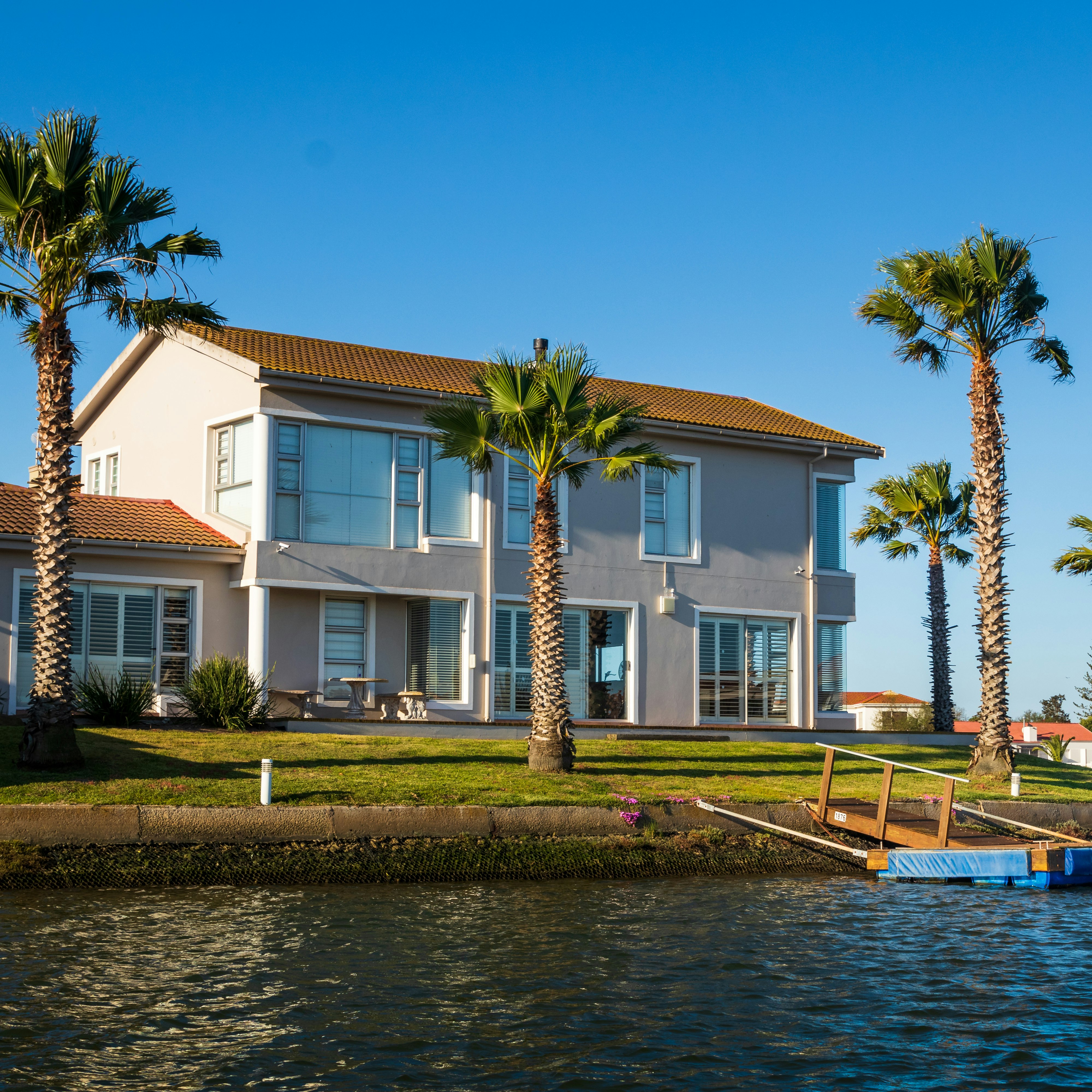 white and brown concrete house beside body of water during daytime