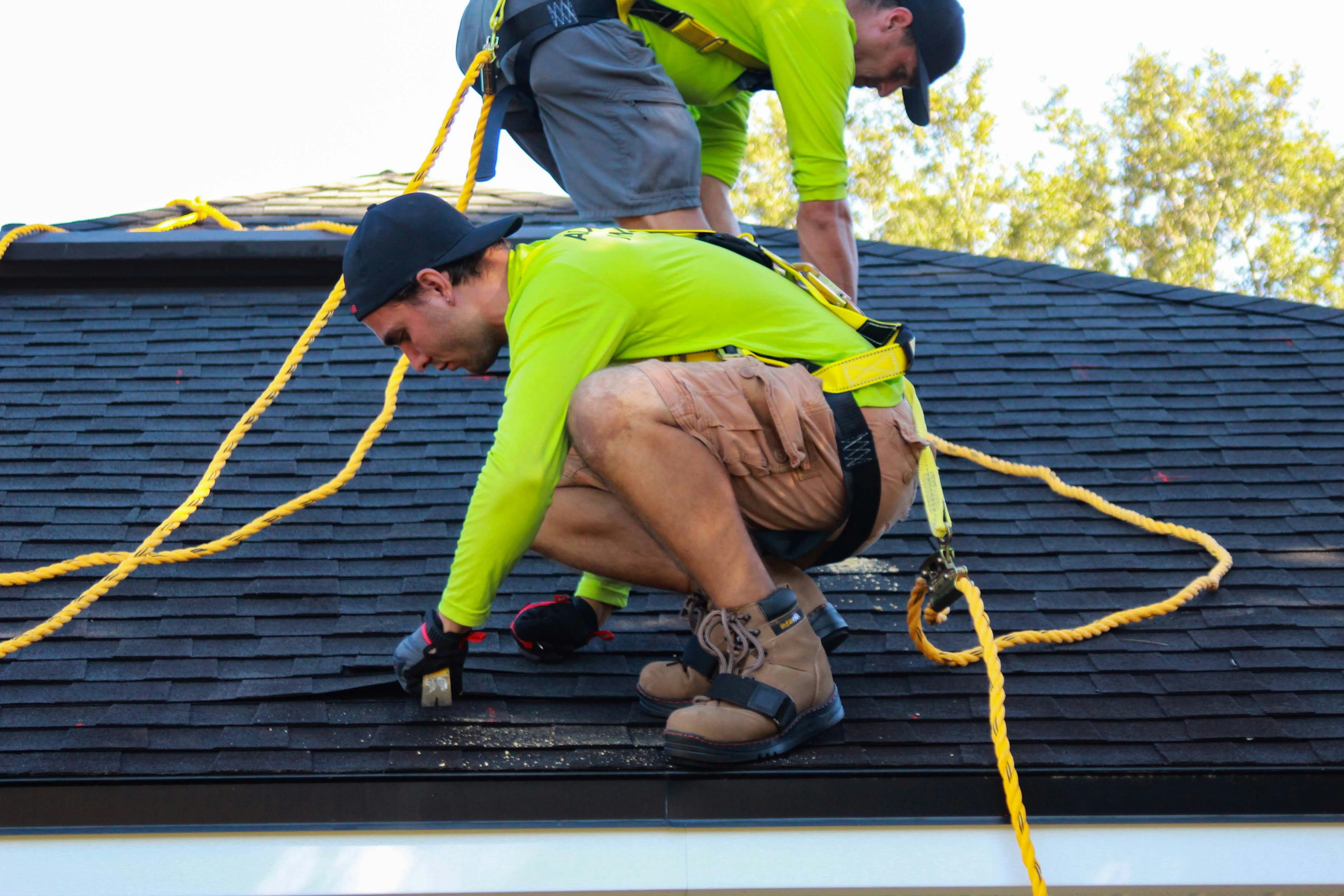 two men repairing the roof of a house