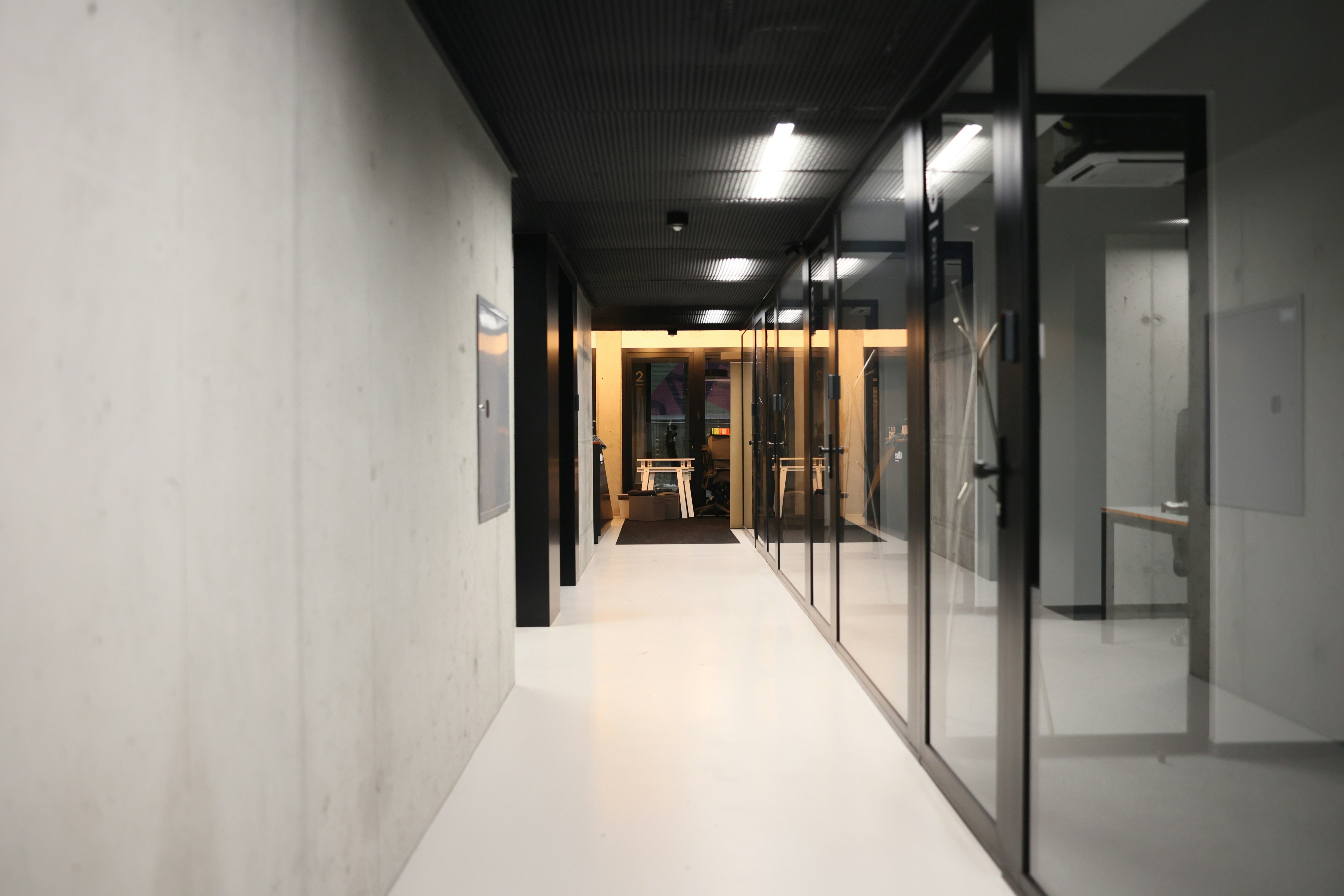 a long hallway with glass walls and a white floor