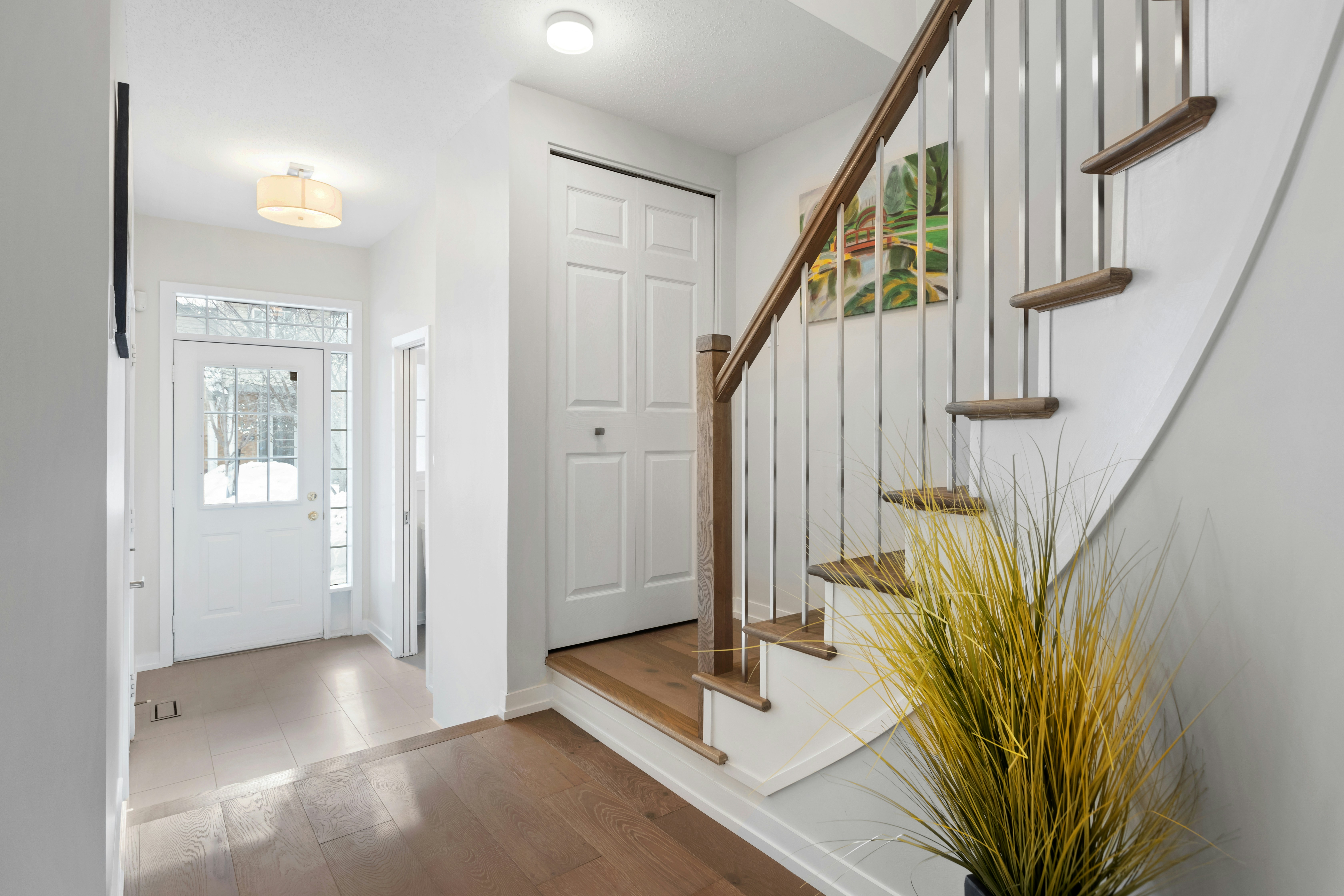 a white staircase with wooden handrails and a potted plant