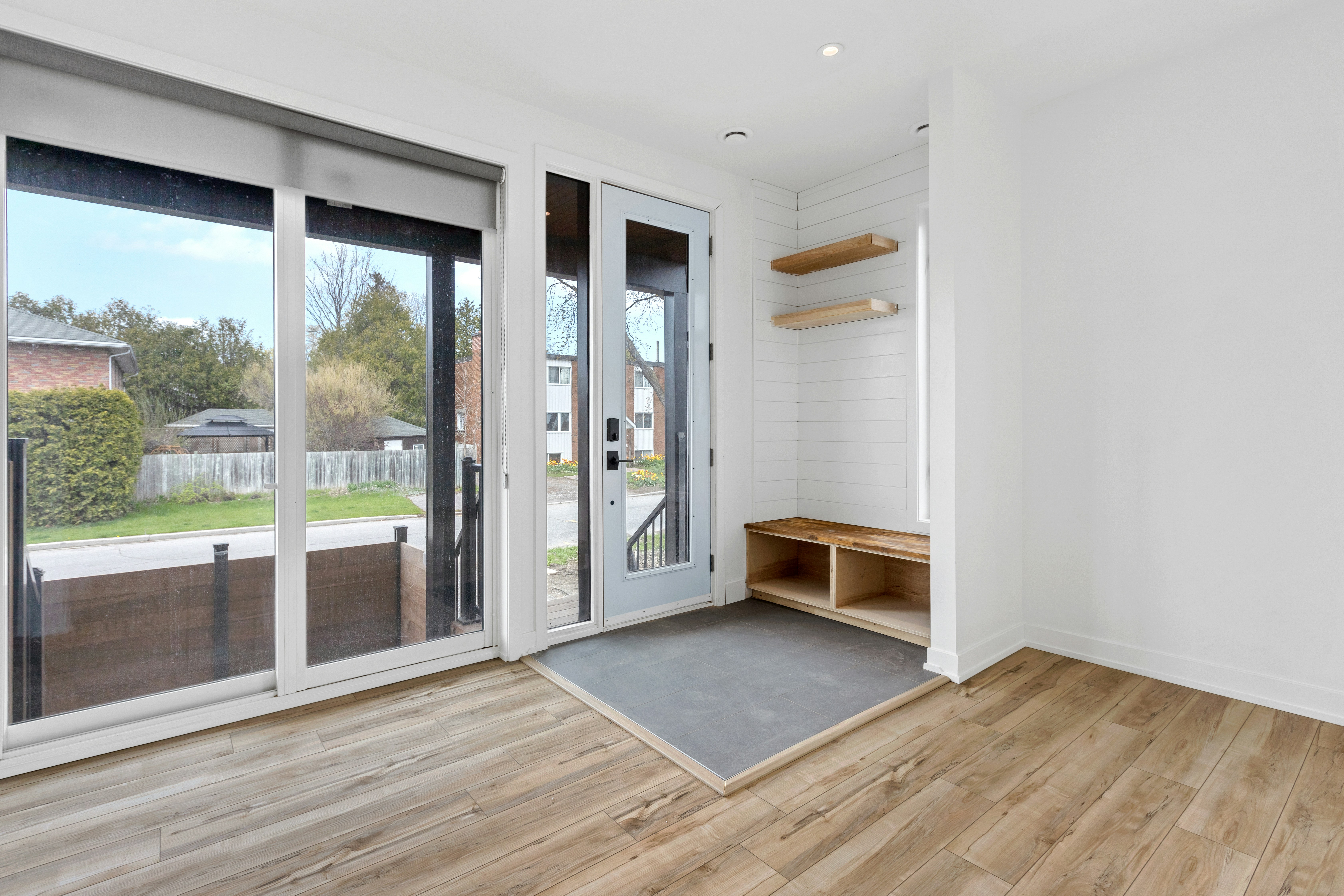 a room with a wood floor and a glass door with a rug and a wood floor with a