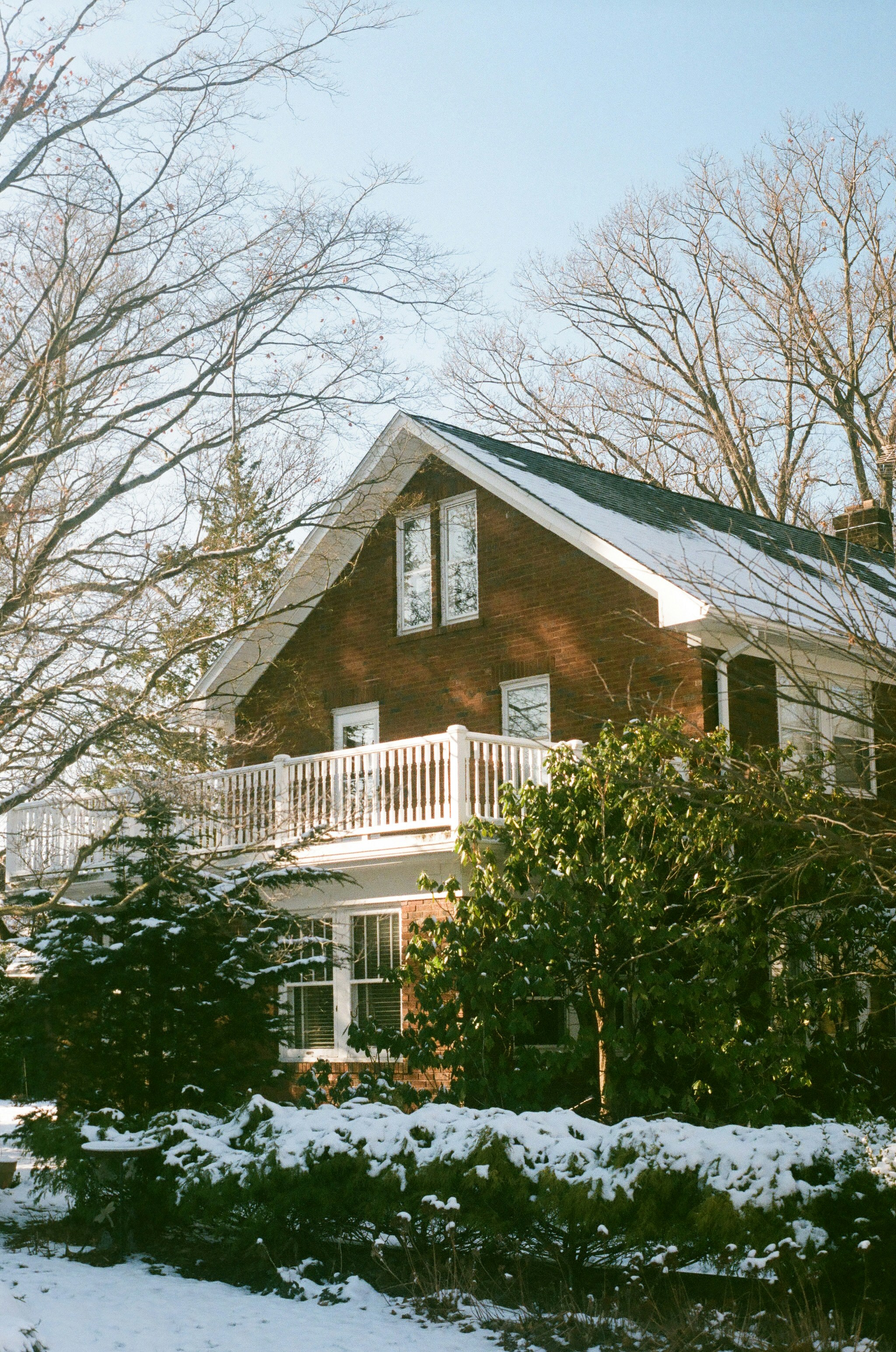 a red house with a white porch in the snow