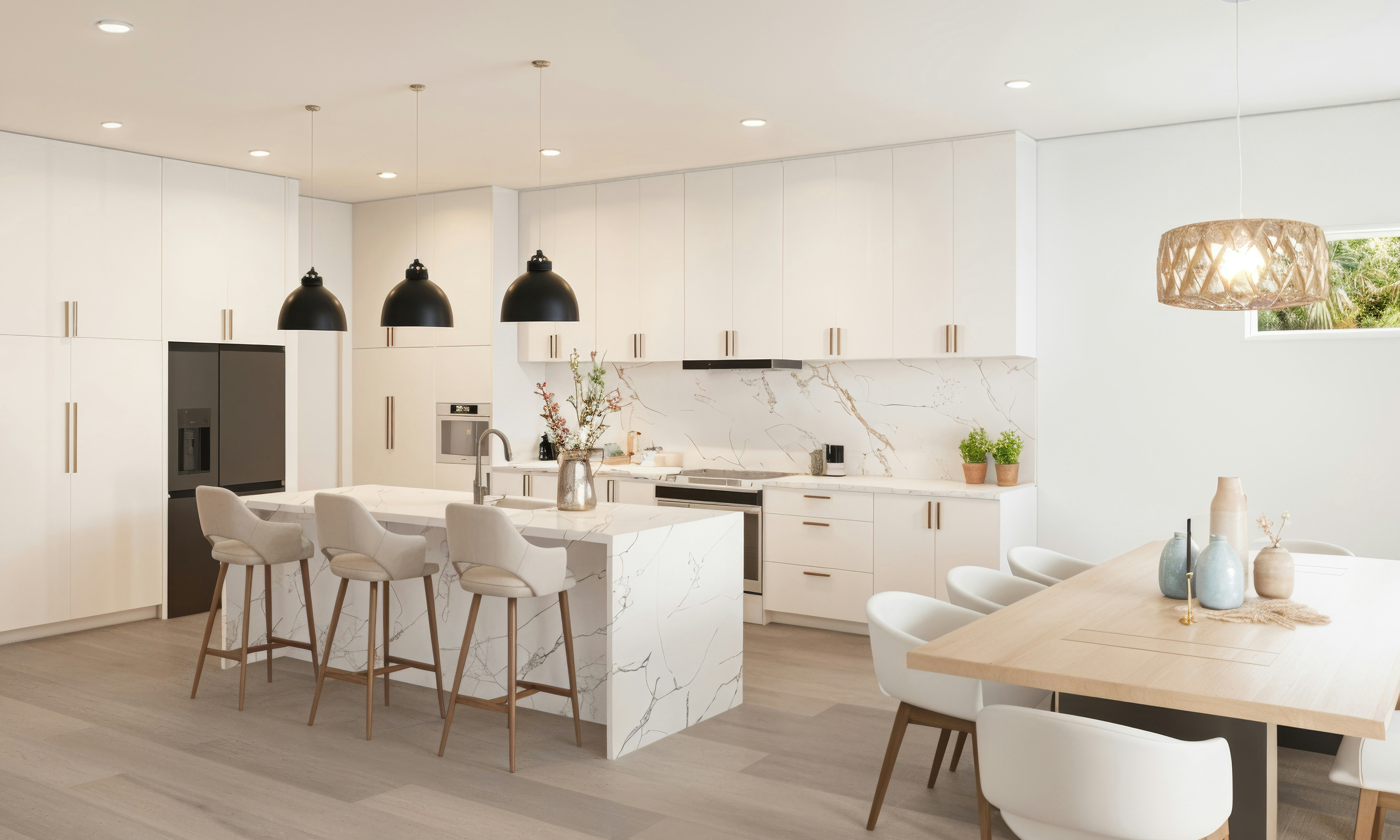 Modern white kitchen with marble island and dining area.