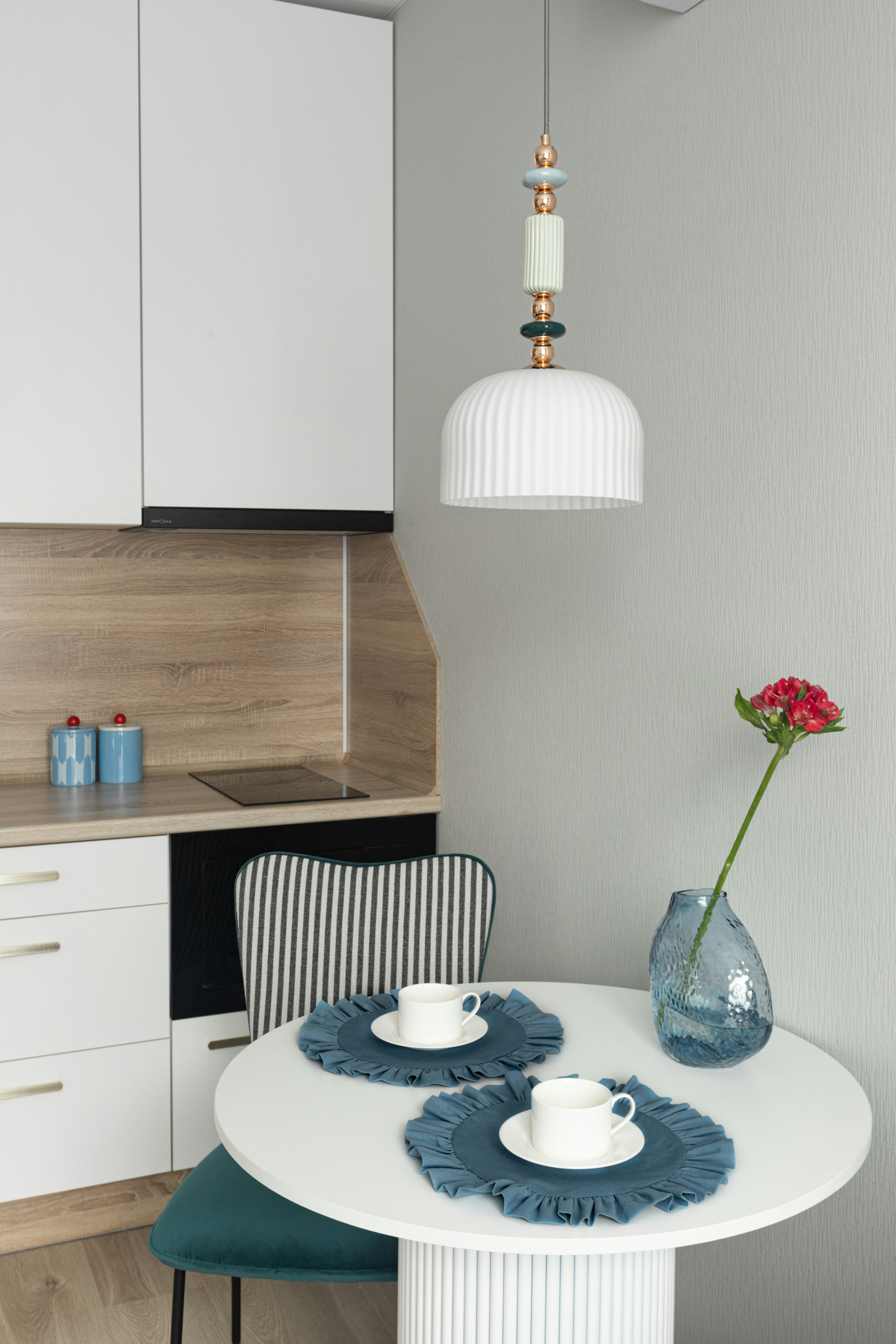 A small dining table with two cups and a flower.