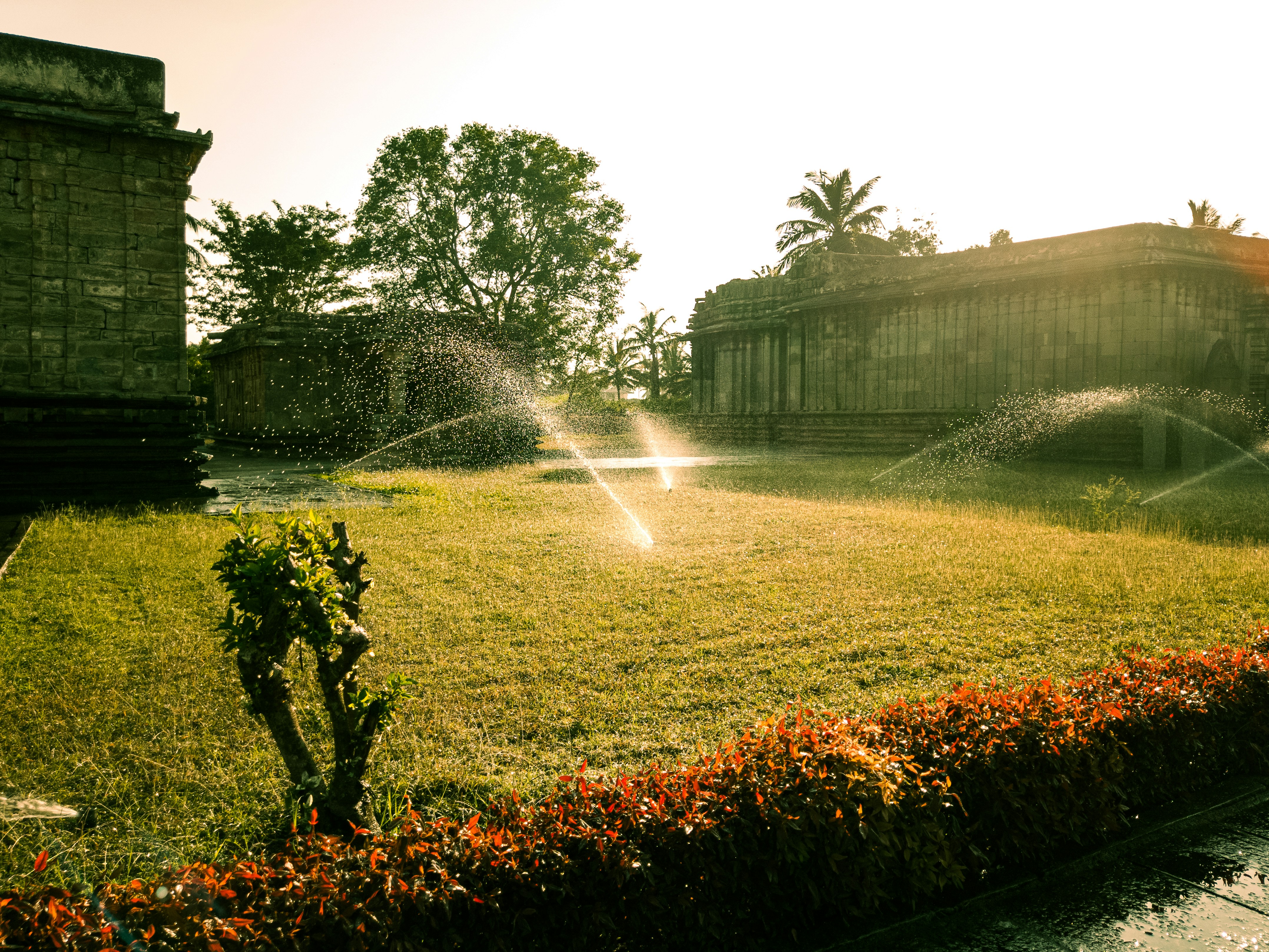 Sprinklers watering a grassy area near old buildings