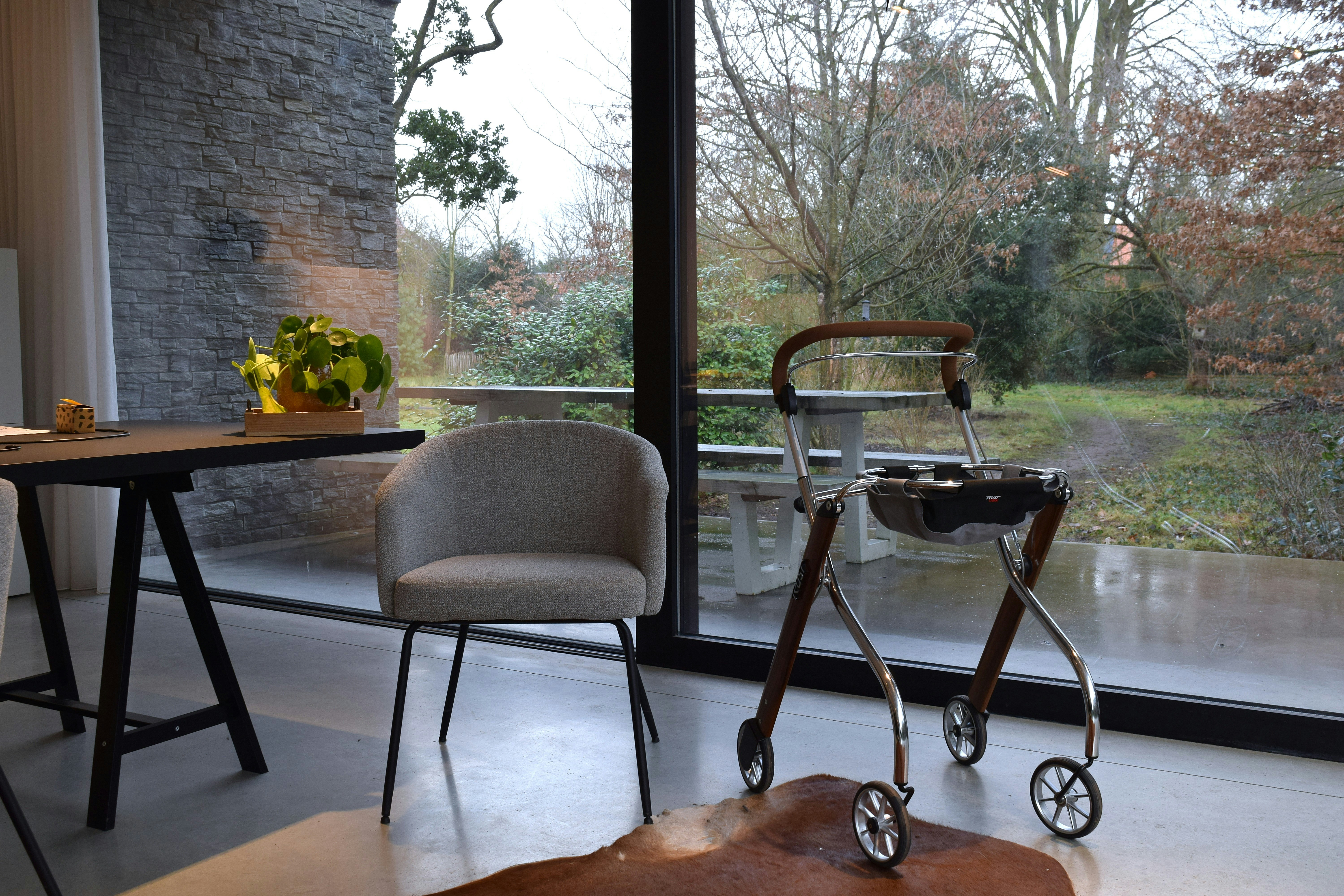 A walker and chair by a large window.