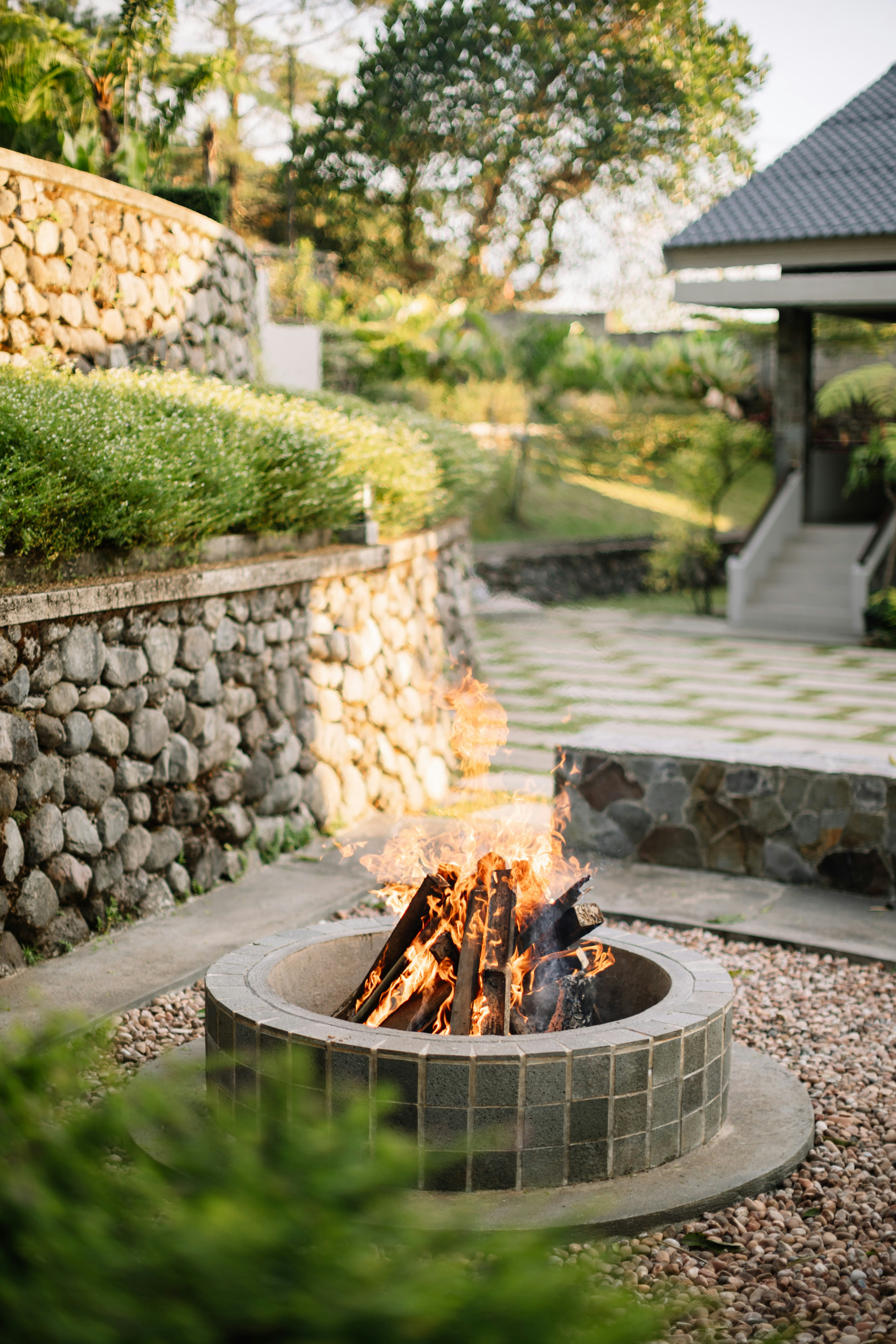 A cozy fire pit with burning logs in a garden.