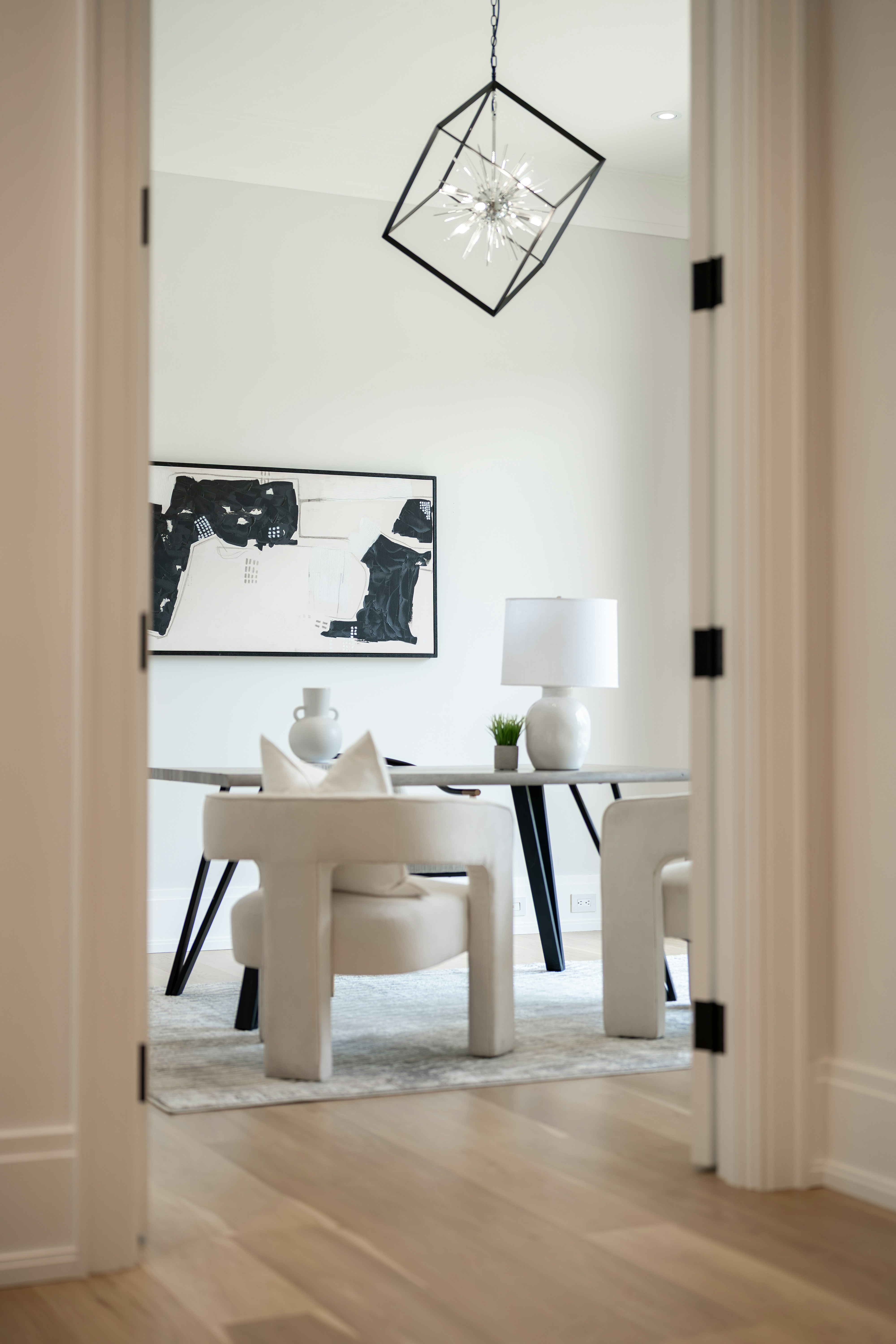 Modern home office with abstract art and geometric chandelier.